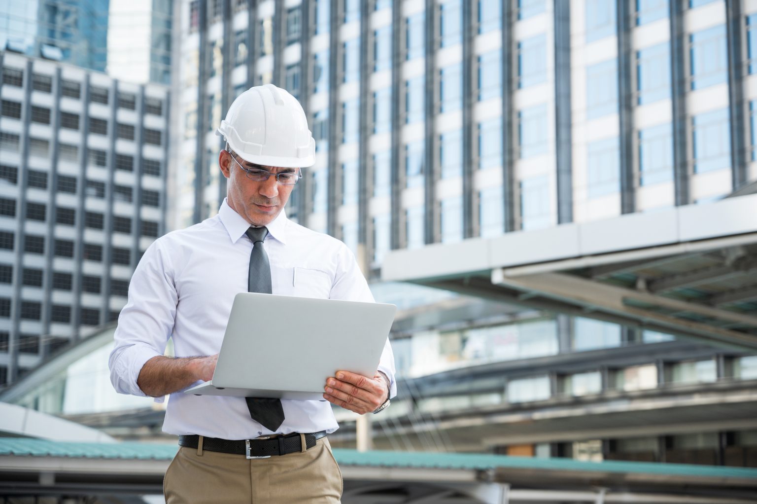 Civil engineering using laptop while working on building construction site.