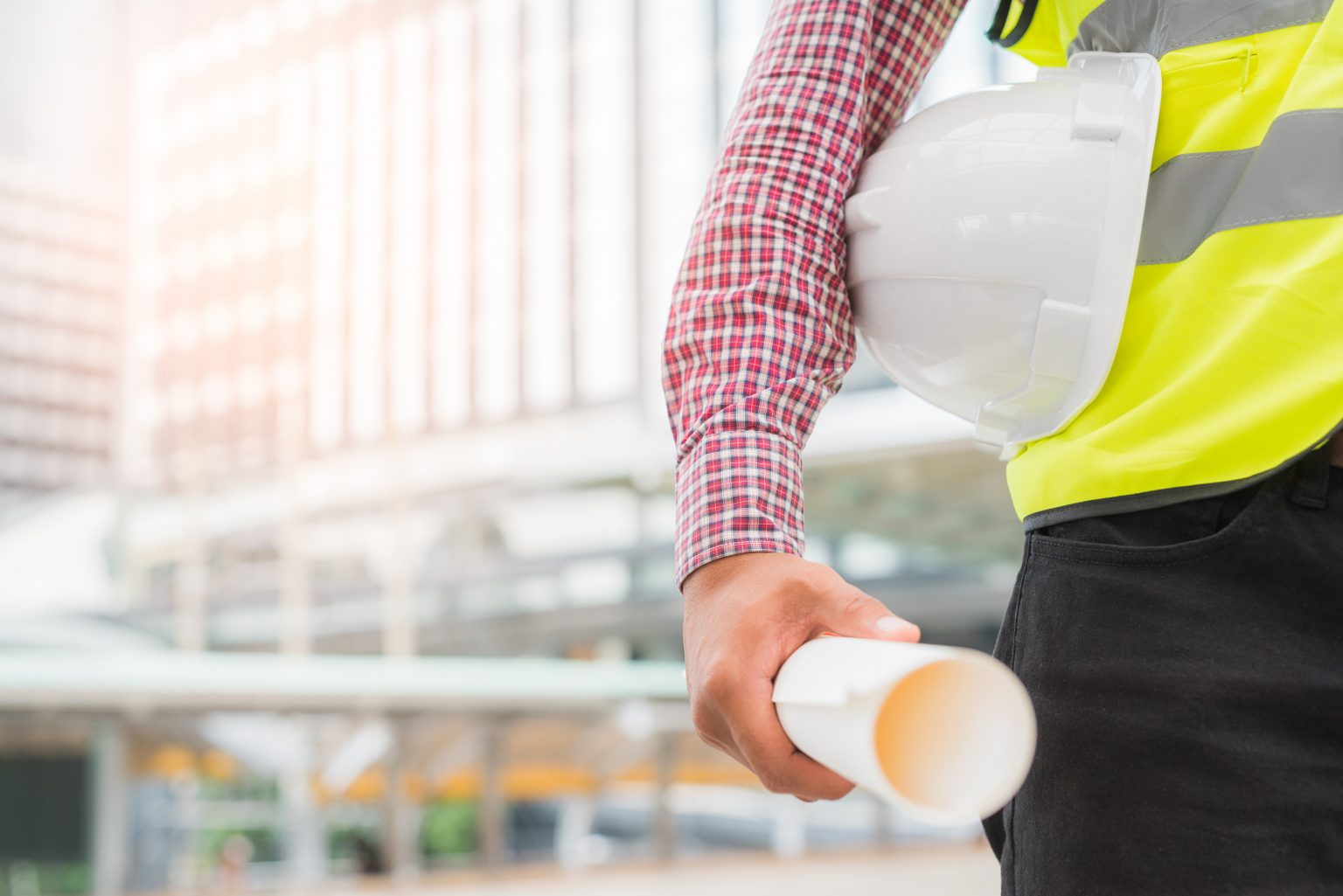Engineering holding safety helmet on building background.